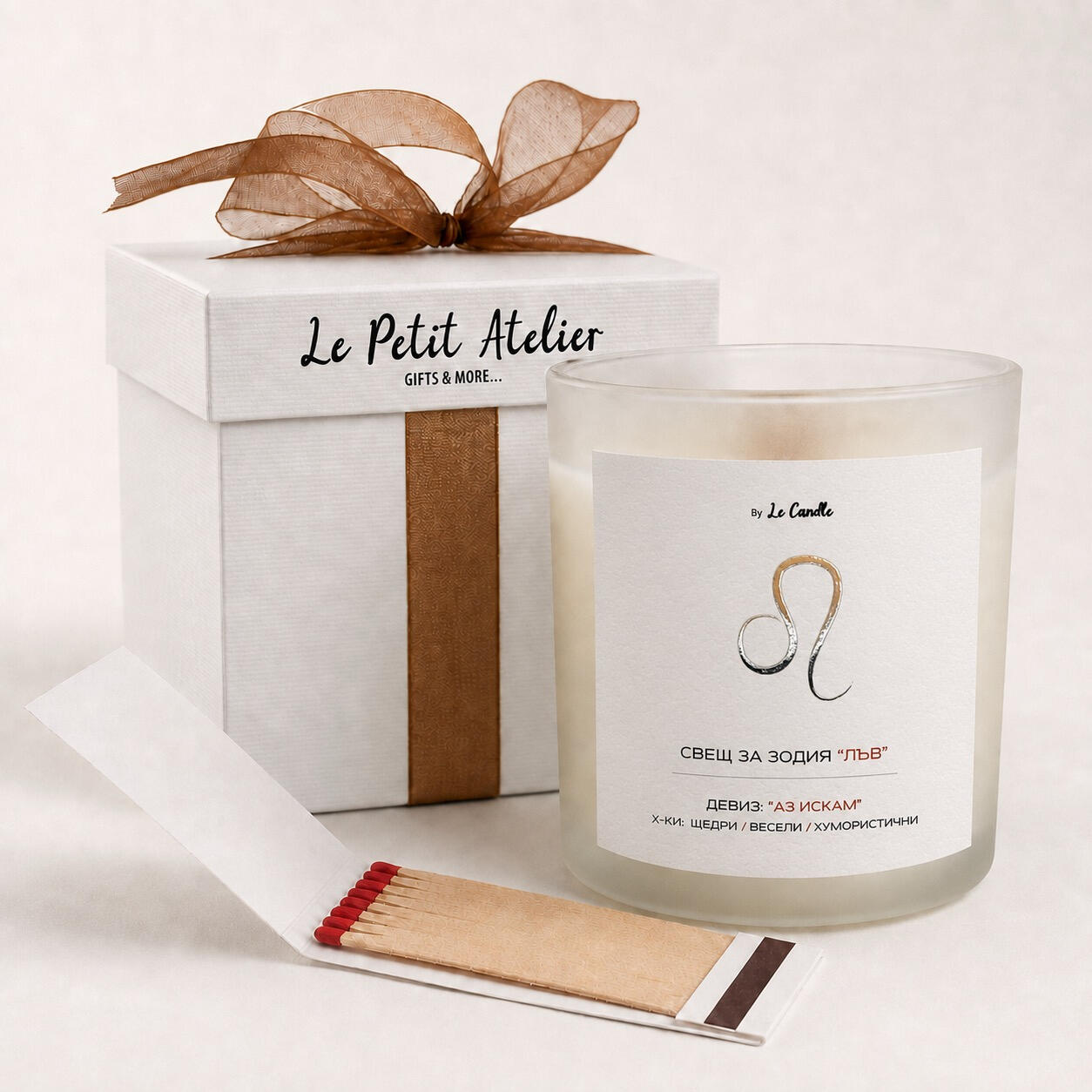 Подаръчен комплект Le Petit Atelier с ароматна соева свещ за зодия Лъв, бронзова панделка, кибритена книжка и бяла кутия.