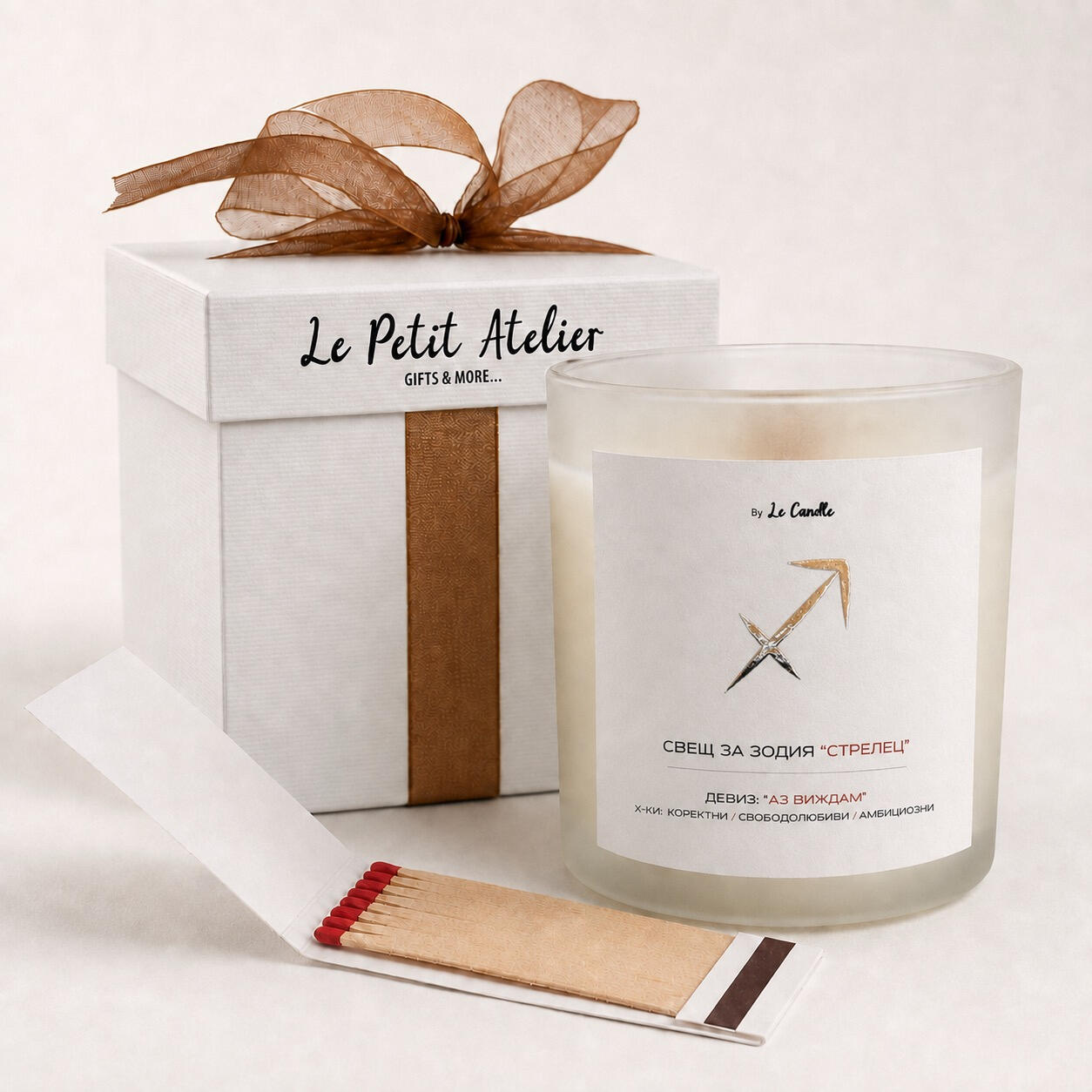 Подаръчен комплект със свещ за зодия Стрелец Подаръчен комплект Le Petit Atelier с ароматна соева свещ за зодия Стрелец, бронзова панделка, кибритена книжка и бяла кутия.